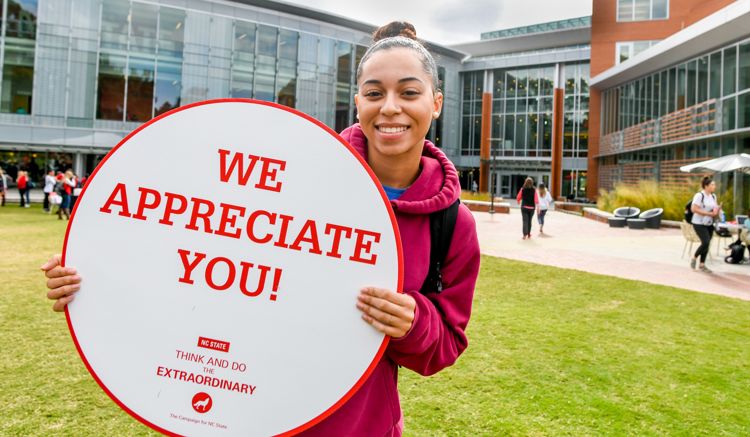 College student holds sign saying "We appreciate you"