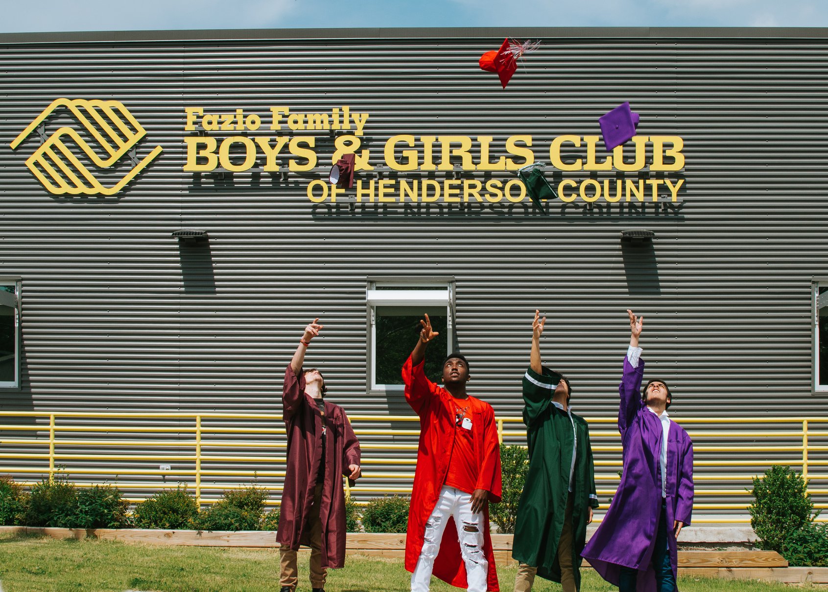 four young adults throwing graduation caps in the air