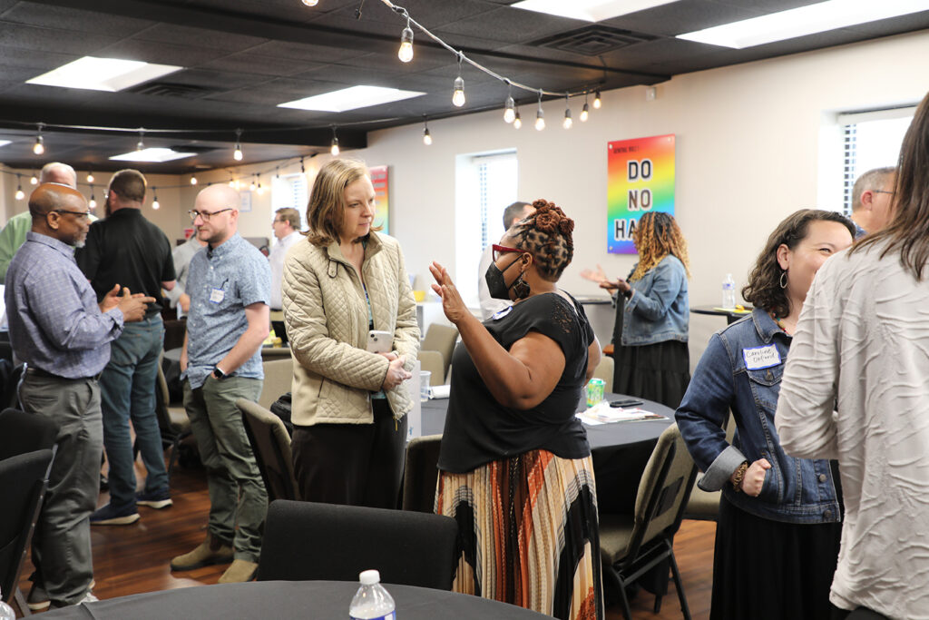 A group of people stand talking to each other in pairs as part of an event