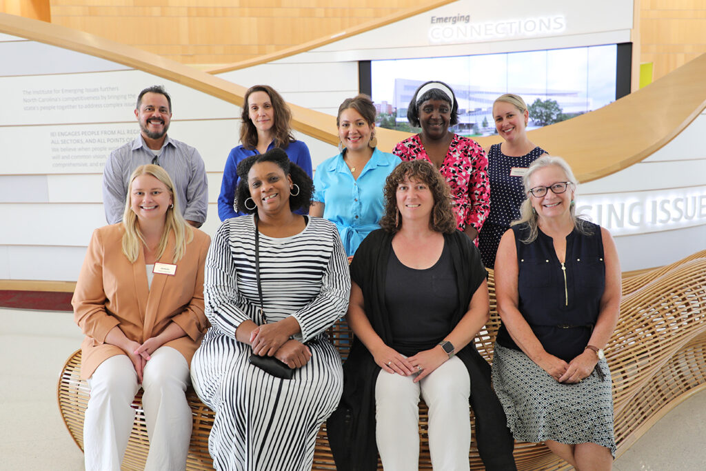 Nine people pose in two rows for a group photo