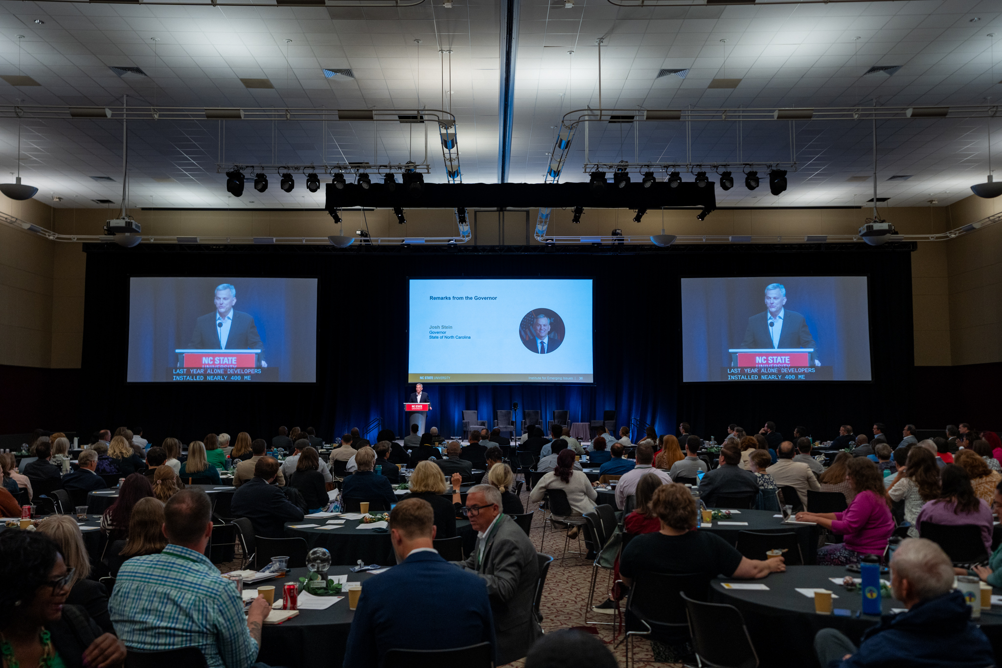 Attendees at the 2025 Emerging Issues Forum watch a speaker on stage in the main conference room.