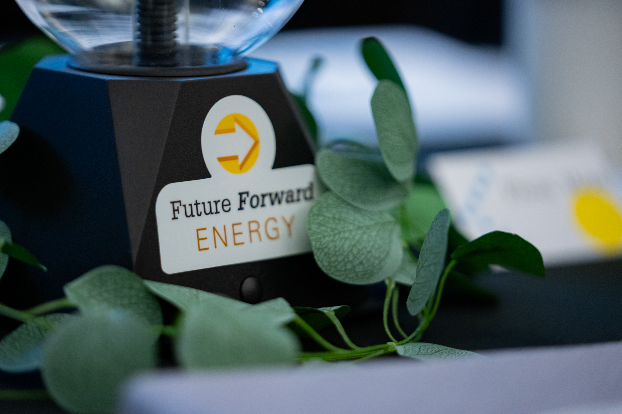 Close-up shot of a black and clear plasma ball with a yellow "Future Forward Energy" logo sticker on the front.